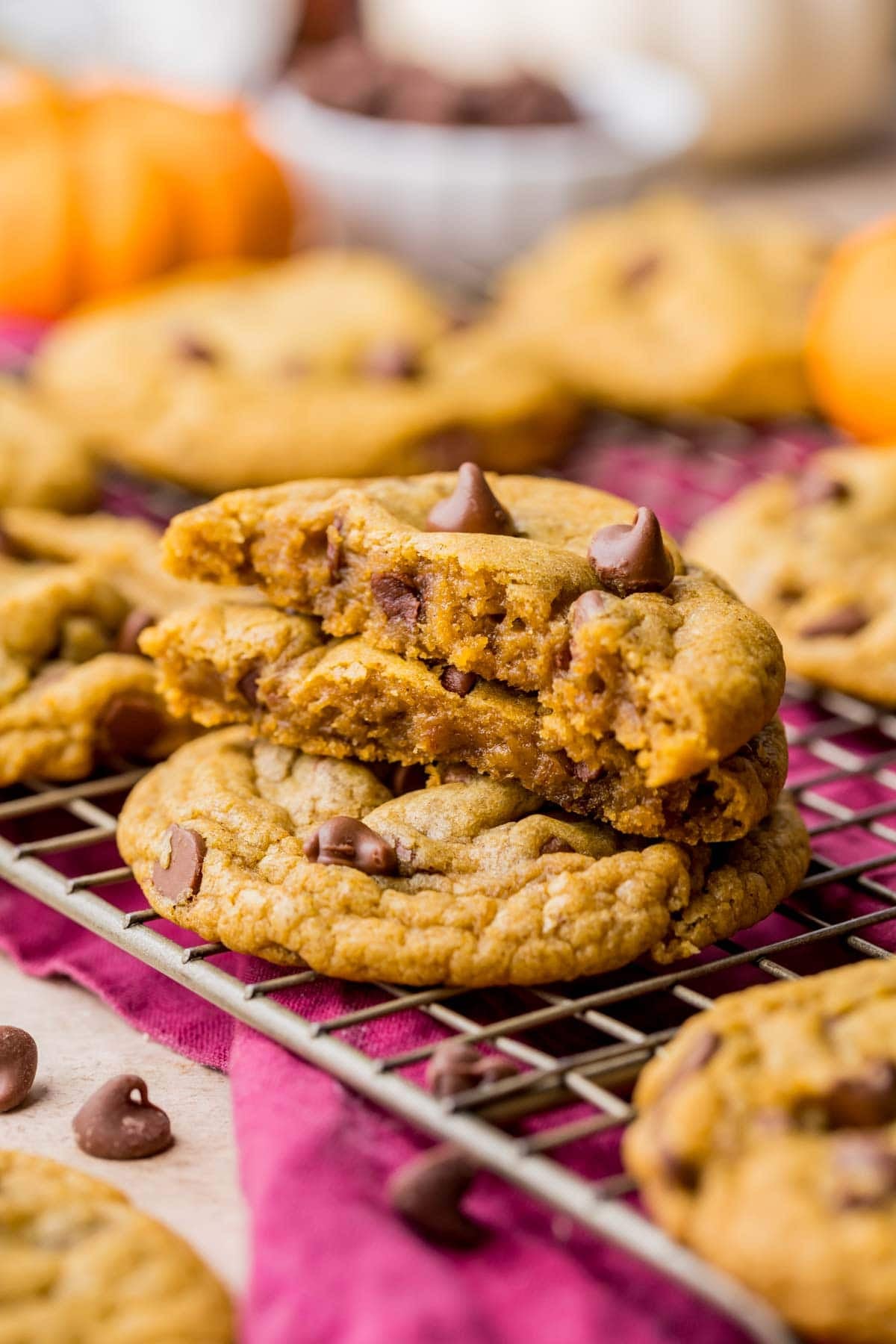 A pumpkin chocolate chip cookie broken in half to show gooey soft center stacked on another cookie.