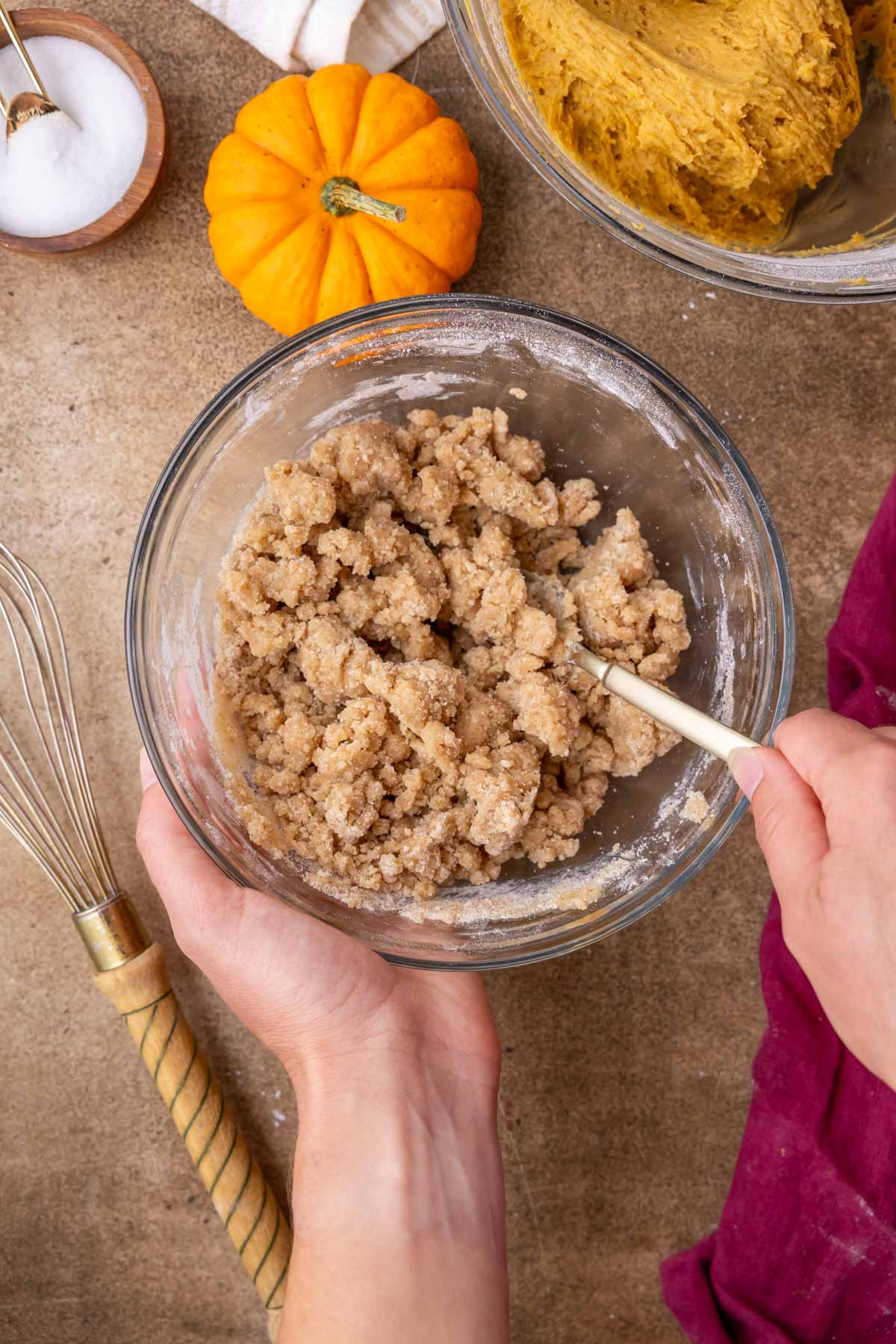 Over head view of a bowl of clumpy streusel being clawed together.