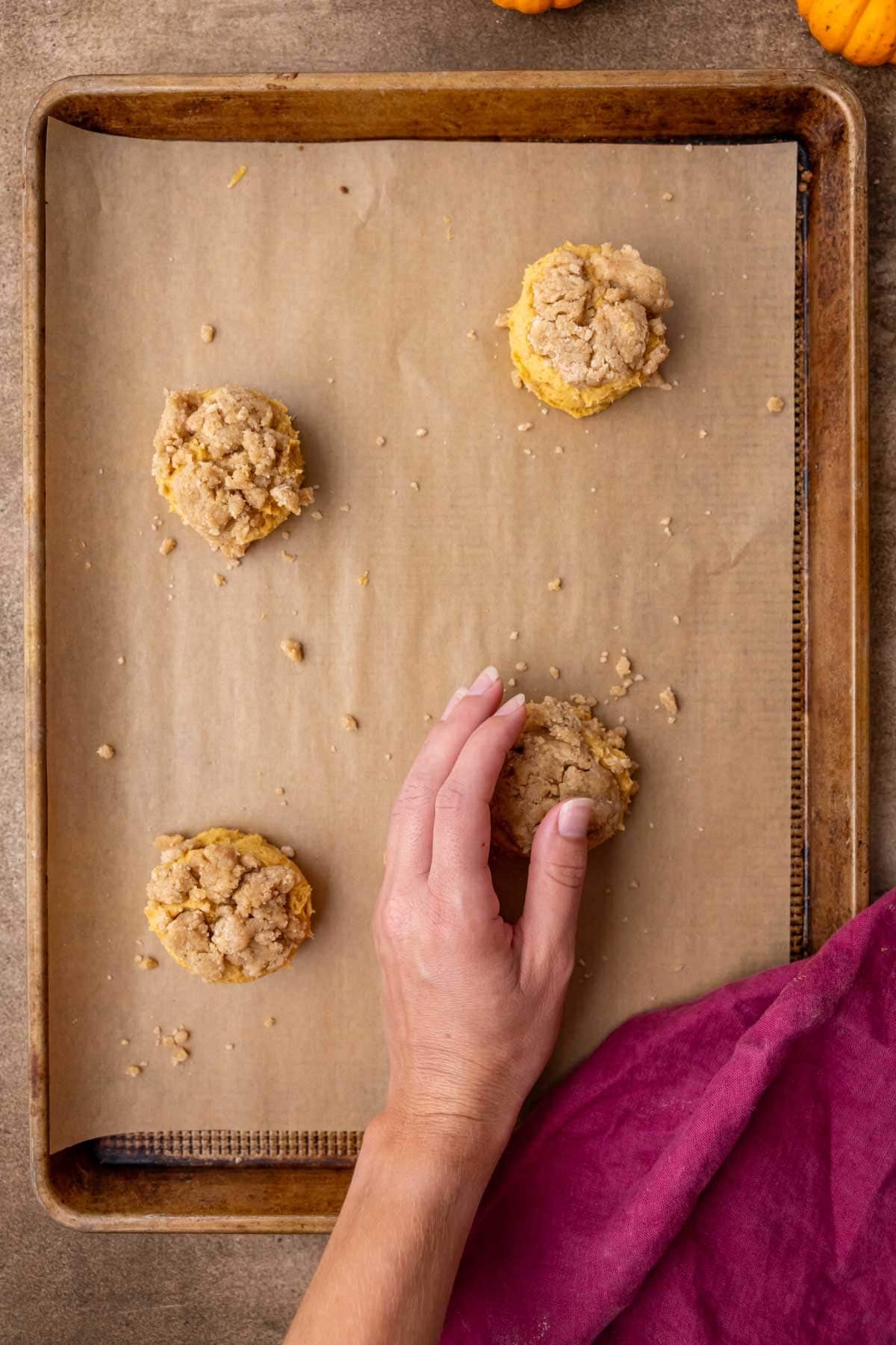 Layering streusel over pumpkin cookie dough that has been stuffed with streusel.