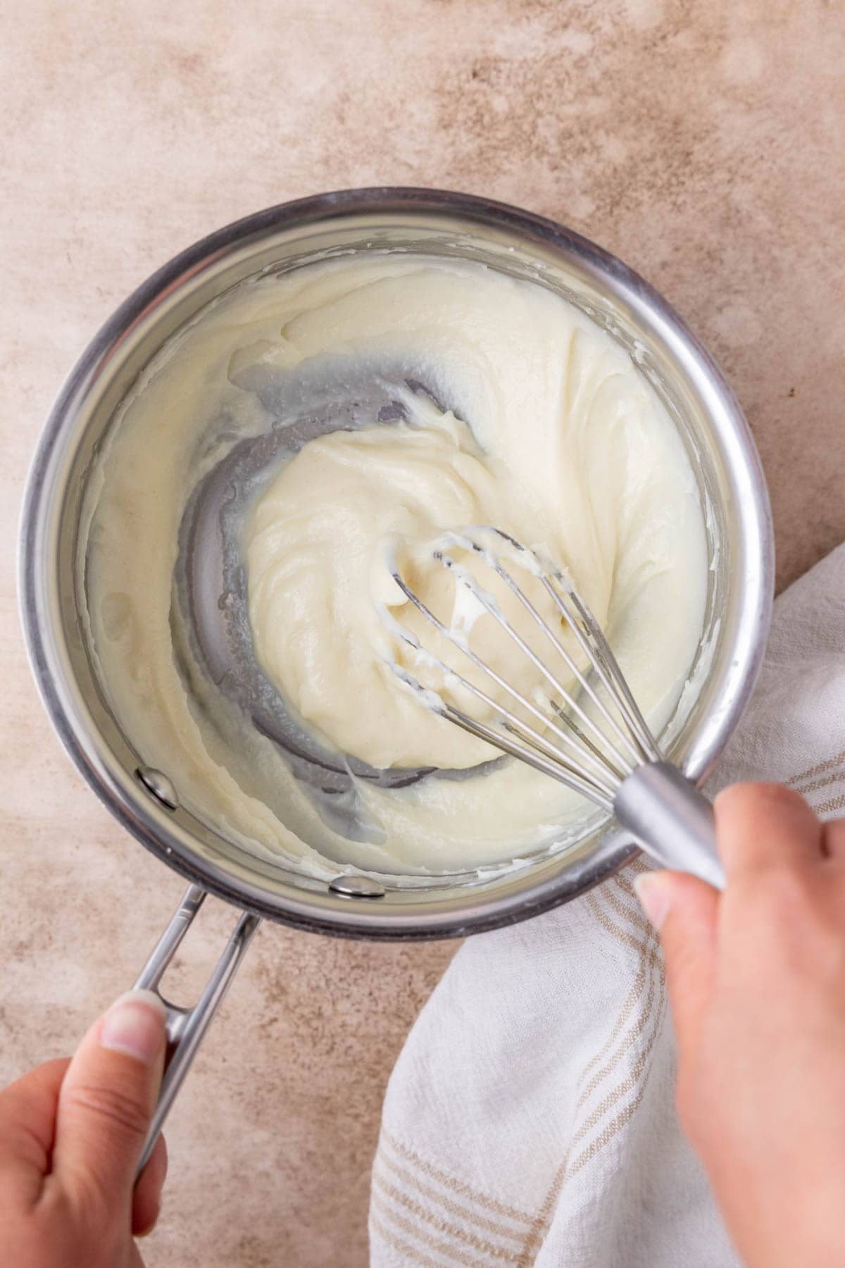 Milk and flour being whisked into tangzhong in a small saucepan.