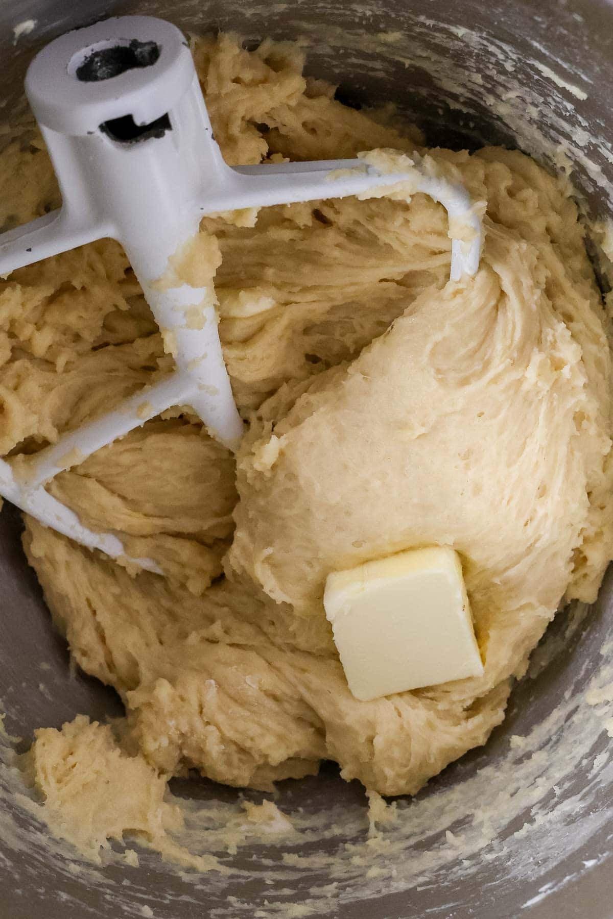 Butter being incorporated into dough one tablespoon at a time.