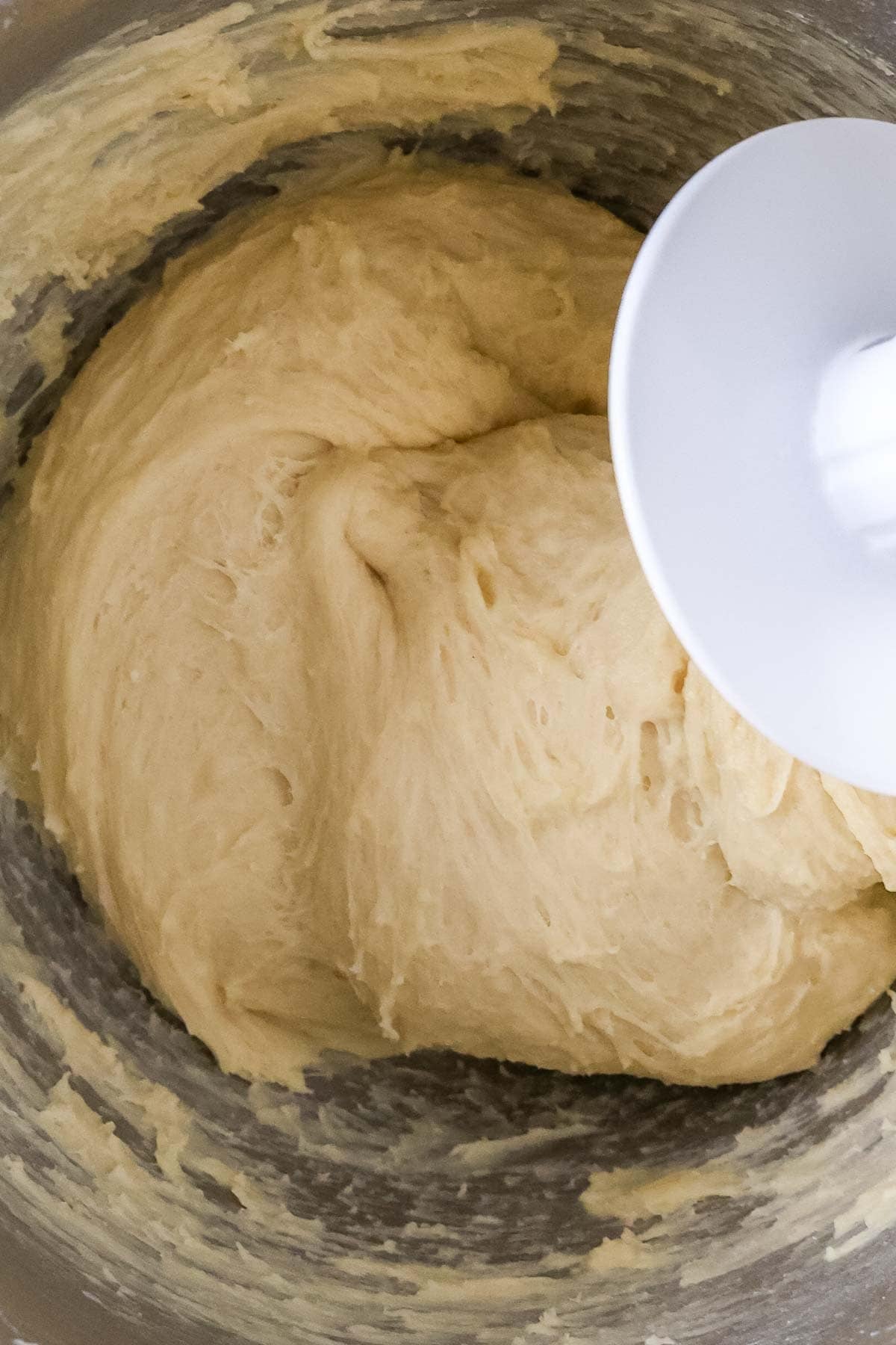 Close-up view of smooth and elastic dough being mixed with a dough hook.