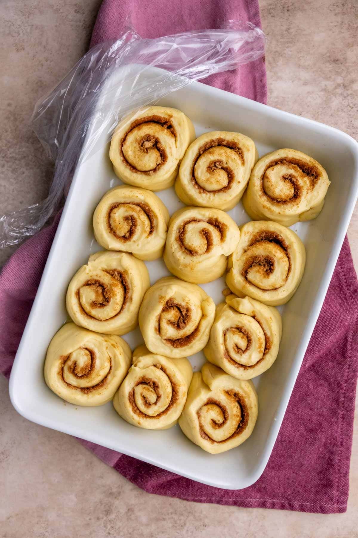 Overhead view of cinnamon rolls in a baking dish after a second rise.