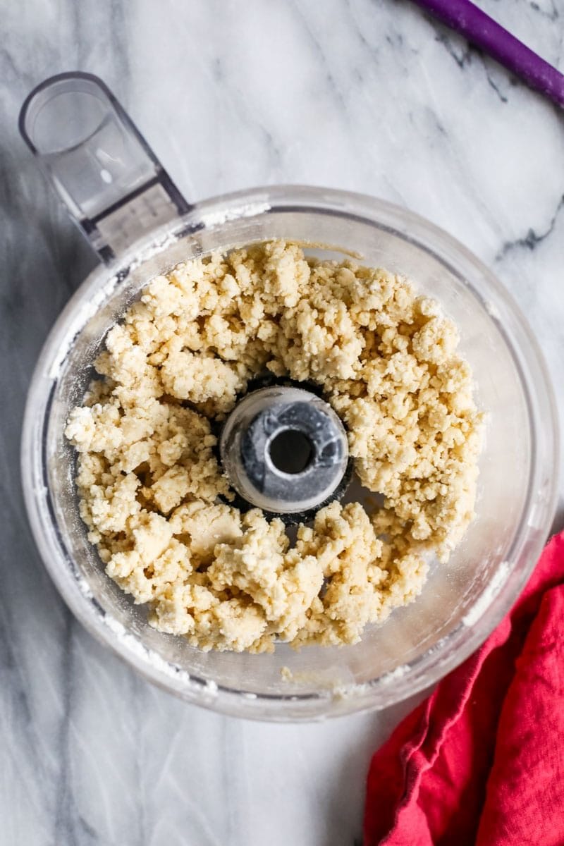 Overhead view of a shaggy sourdough pie crust in a food processor.
