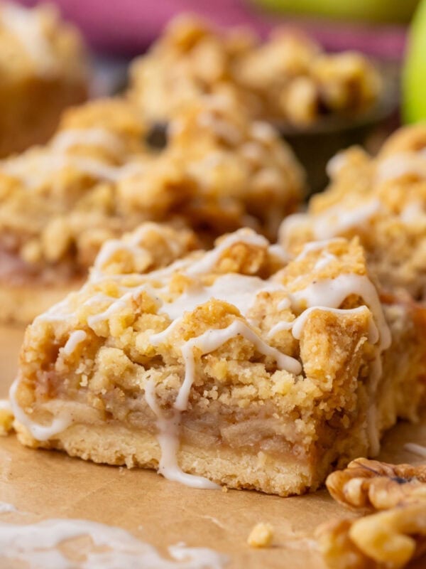 Close-up of apple pie bars made with a shortbread crust, apple filling, crumb topping, and vanilla glaze drizzle.