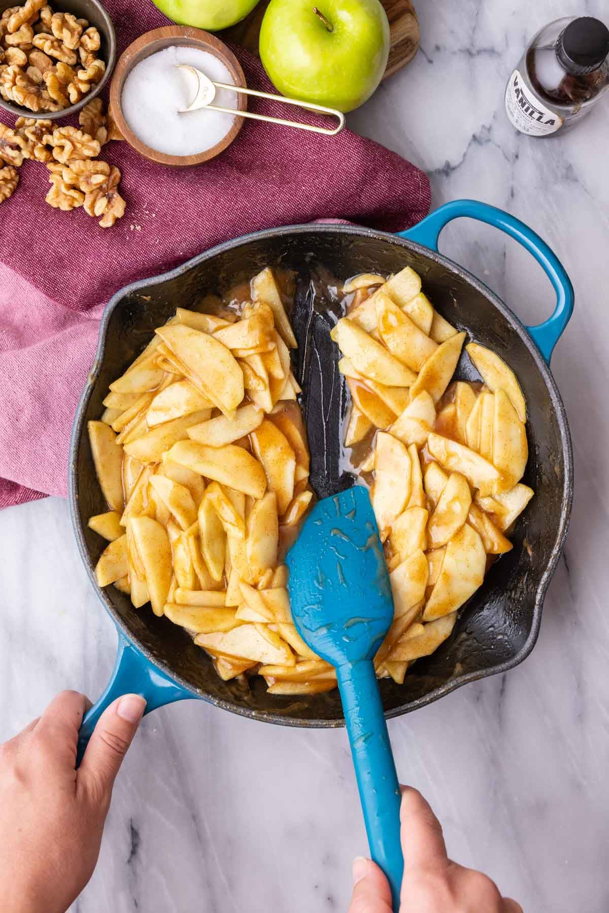 Spatula demonstrating a thickened apple mixture in a cast iron skillet.