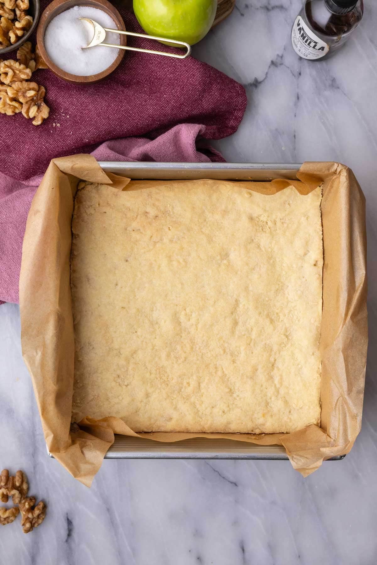Overhead view of a baked crust in a square pan, ready for filling.