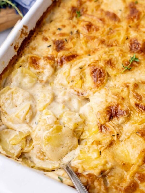 Close-up view of a pan of scalloped potatoes with a golden brown crust and creamy interior.
