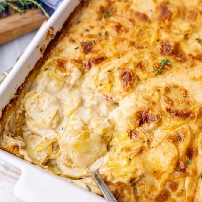 Close-up view of a pan of scalloped potatoes with a golden brown crust and creamy interior.
