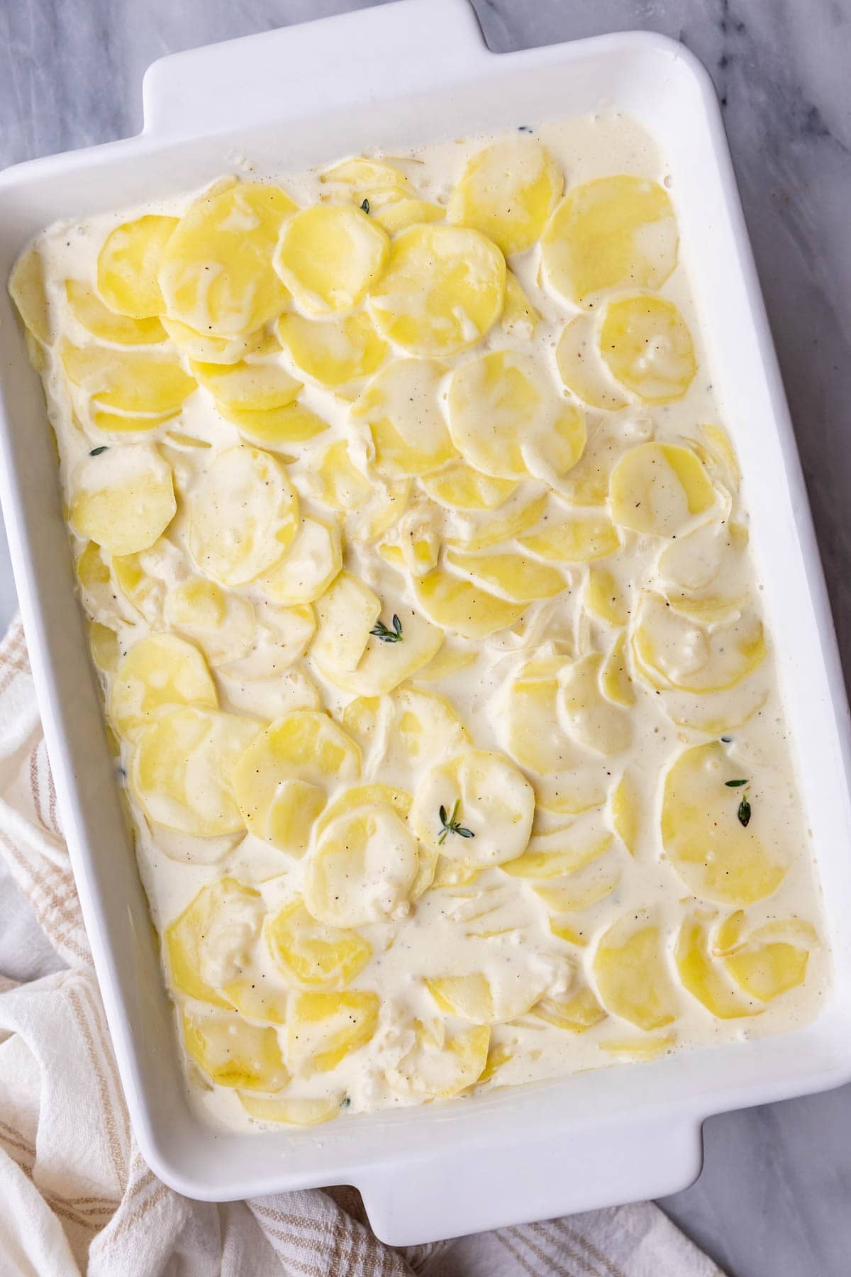 Overhead view of a pan of scalloped potatoes before baking.