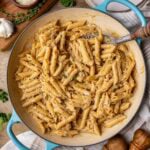 Overhead view of a skillet of French onion pasta topped with fresh parsley and parmesan.