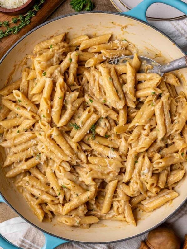 Overhead view of a skillet of French onion pasta topped with fresh parsley and parmesan.