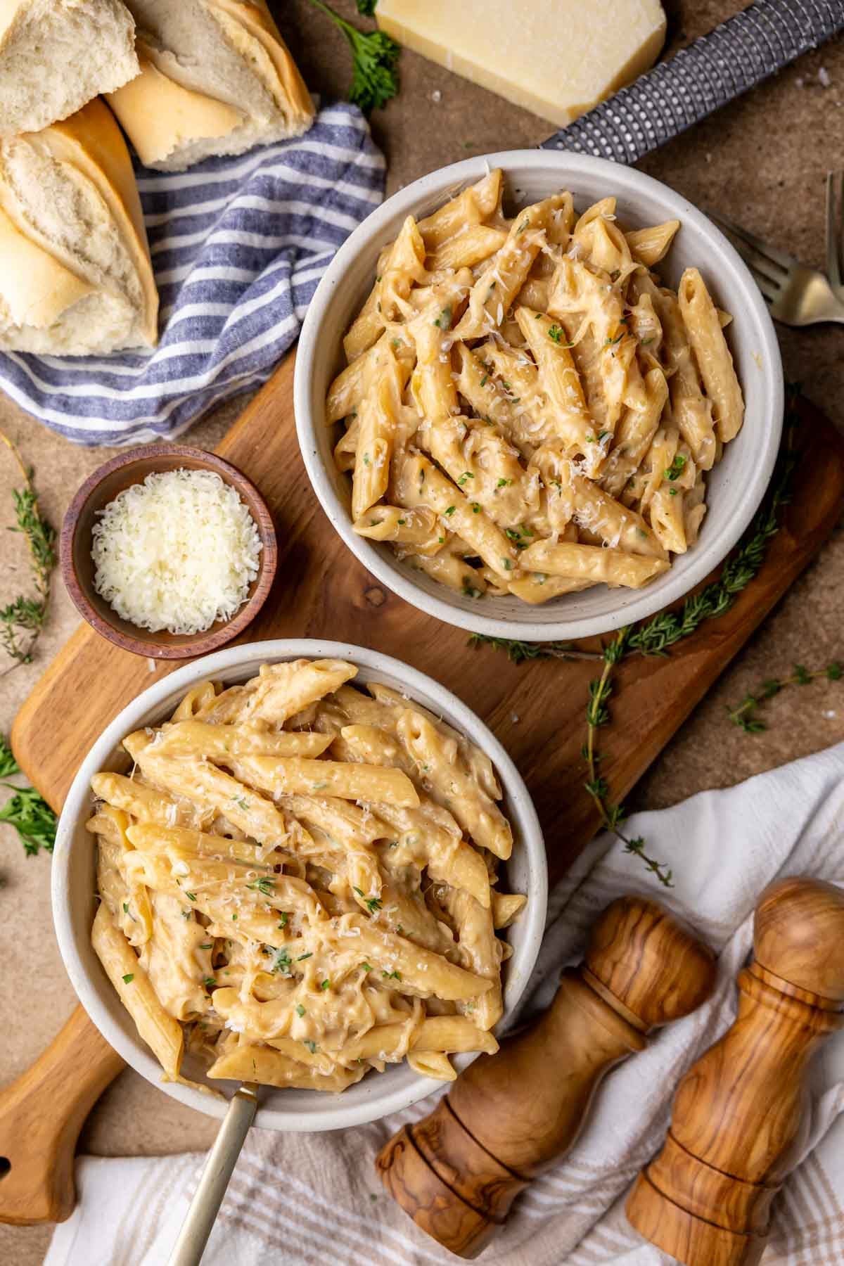 Two bowls of French onion pasta topped with grated parmesan and parsley.