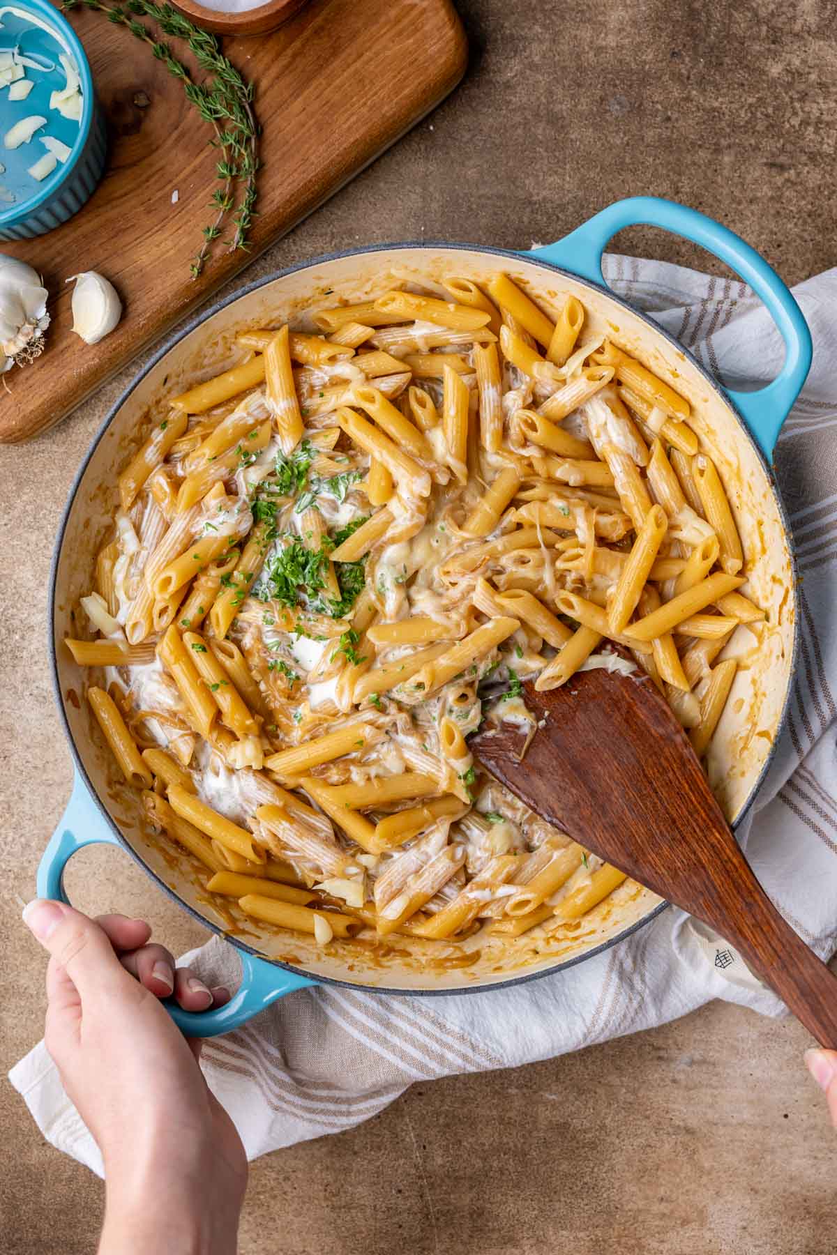 Stirring parmesan and parsley into pasta in a skillet.