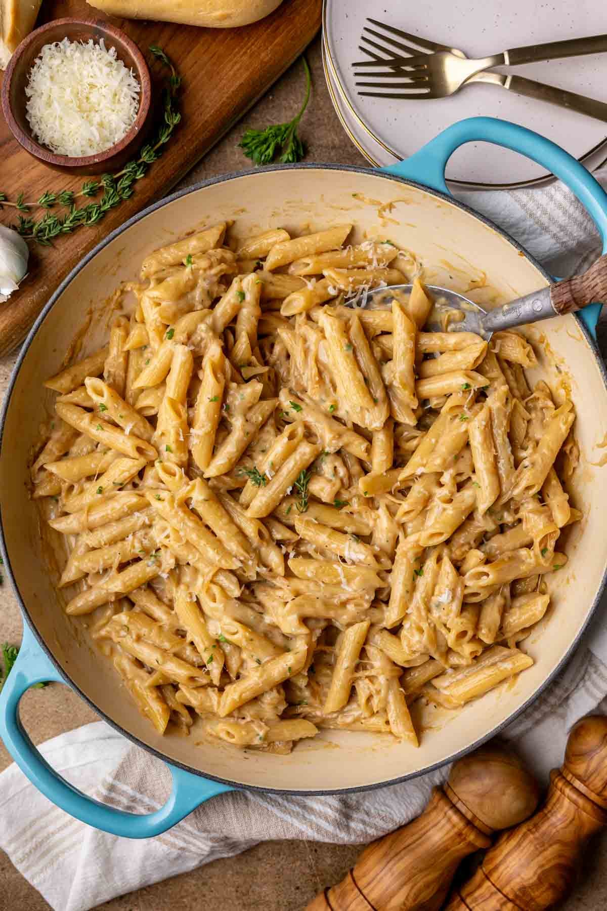 Overhead view of a skillet of French onion pasta topped with fresh parsley and parmesan.