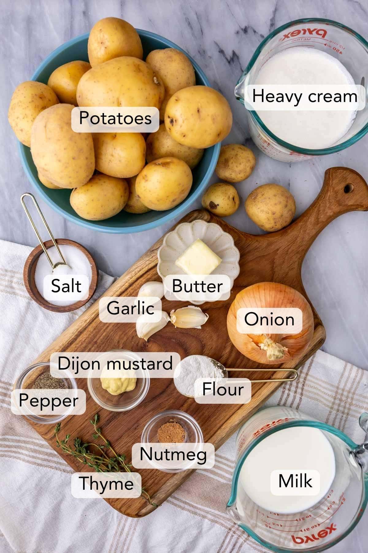 Overhead view of ingredients including potatoes, spices, onion, milk, cream, and more.