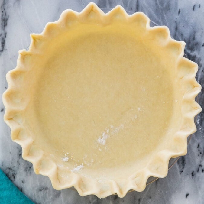 Overhead view of an unbaked pie crust with fluted edges.