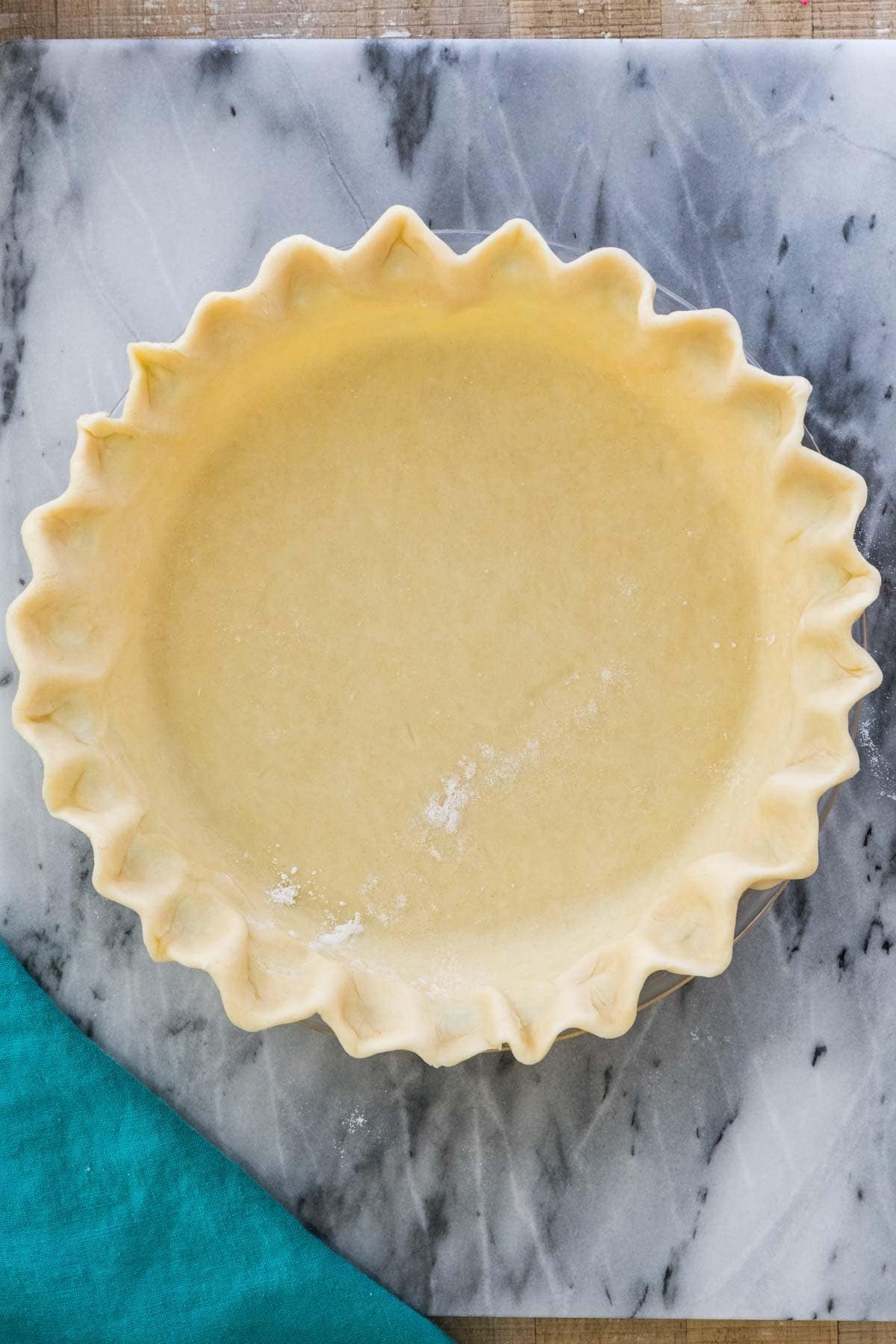 Overhead view of an unbaked pie crust with fluted edges.