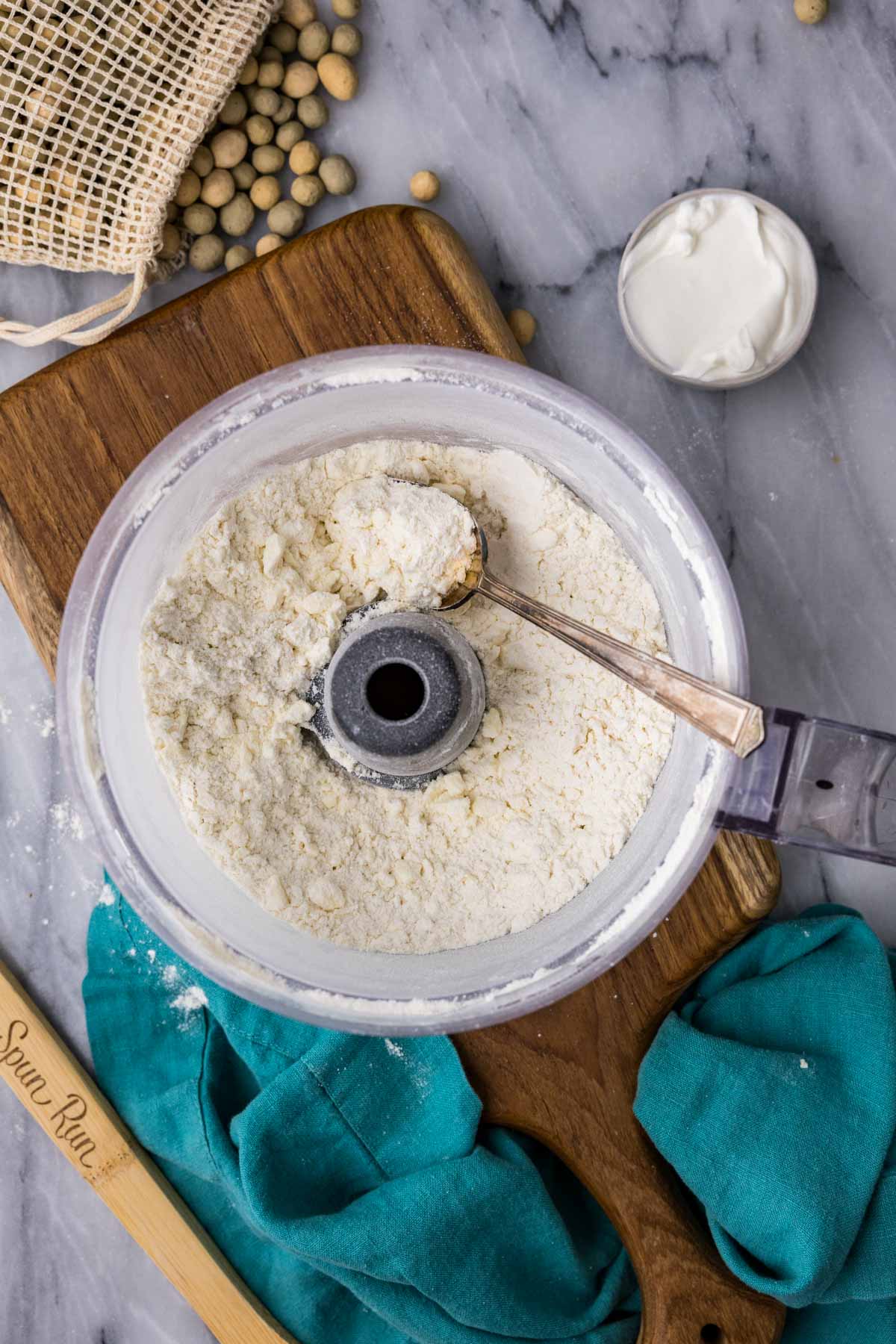 Overhead view of a food processor bowl after pulsing butter into a flour mixture.