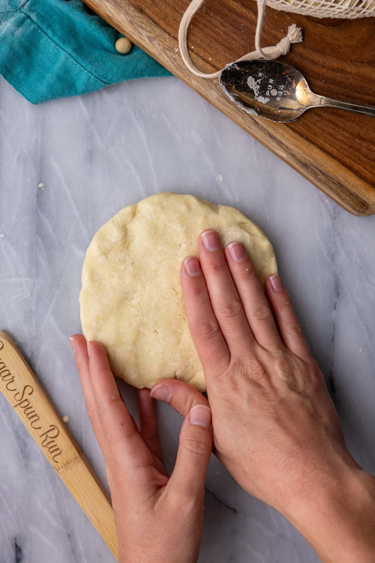 Hands pressing pie dough into a disc.